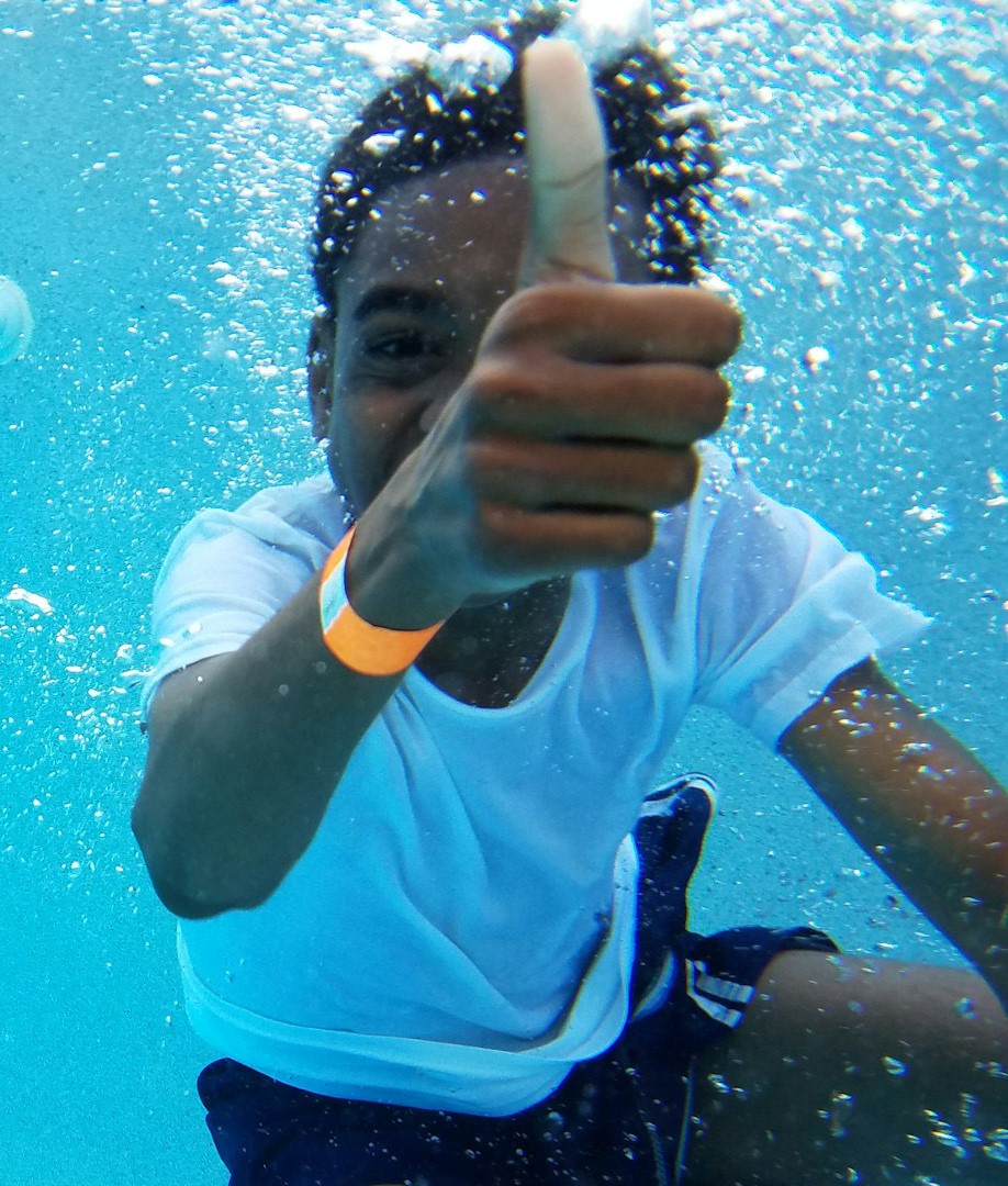 Child underwater giving a thumbs up during a swim lesson